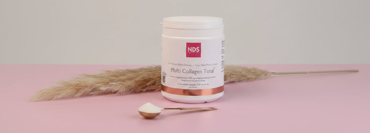 NDS Multi Collagen Total supplement jar with a spoonful of powder on a pink surface.
